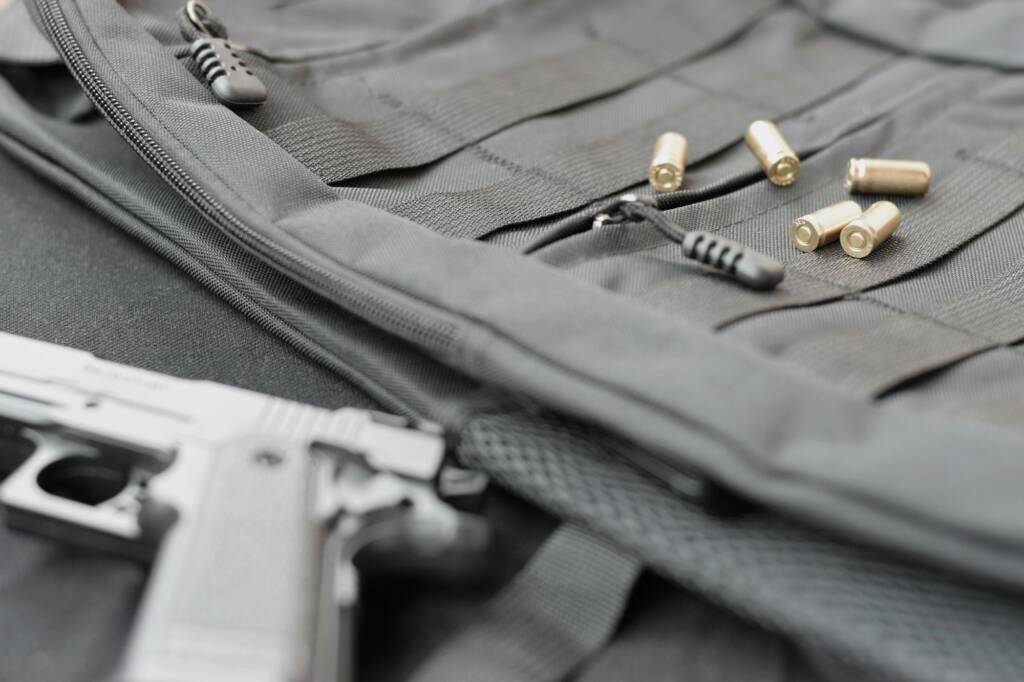 9mm bullets and pistol lie on a black tactical backpack