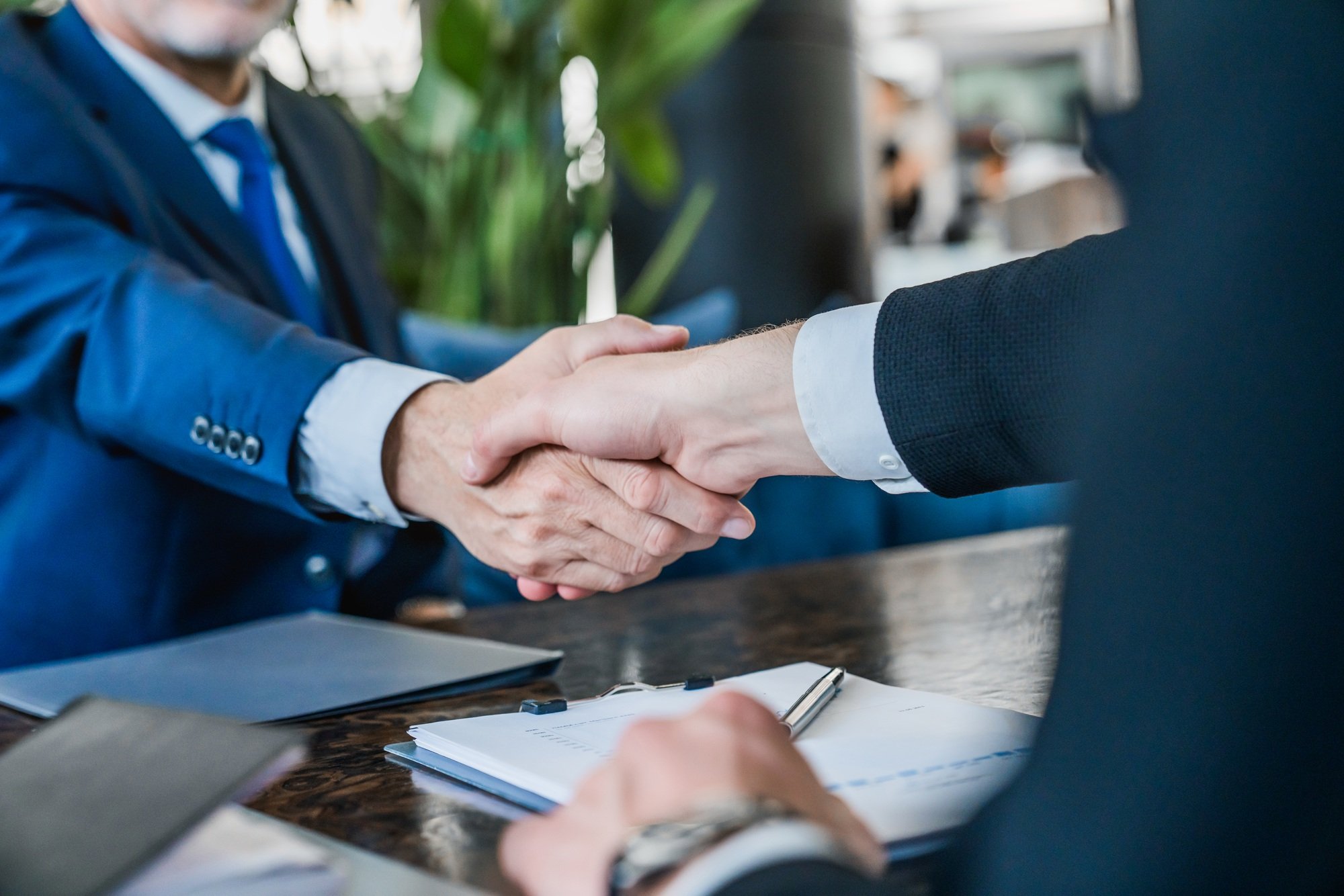 Hands of senior and young businessmen shaking after agreement on meeting